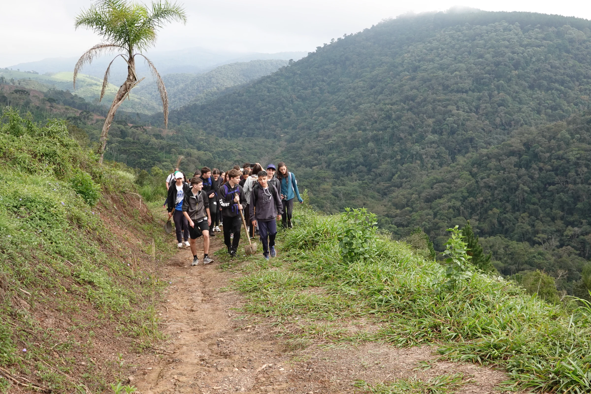 Grupo descendo trilha com vale ao fundo